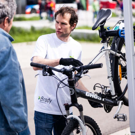 Ein Mann repariert ein Fahrrad und spricht währenddessen mit einem anderen Mann.