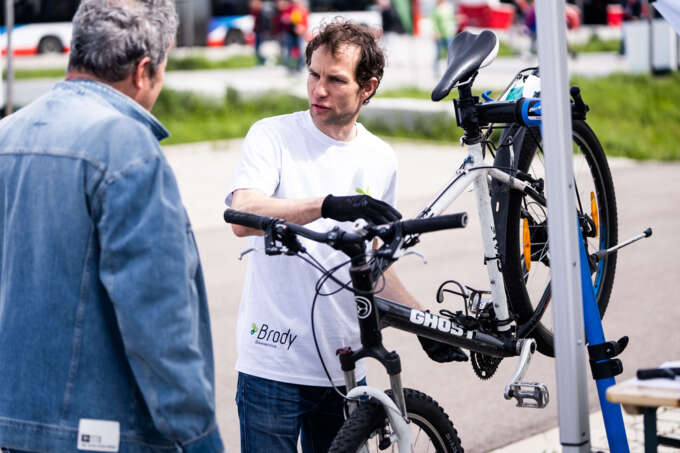 Ein Mann repariert ein Fahrrad und spricht währenddessen mit einem anderen Mann.